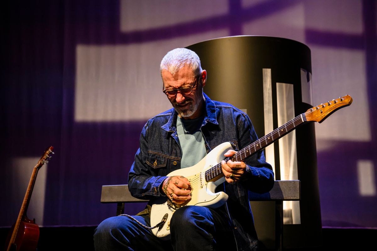 Een man houdt een gitaar vast en kijkt naar de gitaar