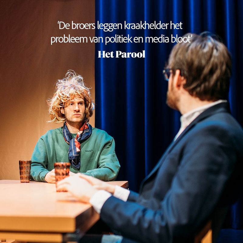Twee mannen zitten tegenover elkaar. De eerste man zit met zijn rug naar de camera toe en de andere man is verkleed als vrouw met een blonde pruik. Ze kijken serieus en zitten aan tafel. Boven hen staat de tekst: de broers leggen kraakhelder het probleem van politiek en media bloot van Het Parool.