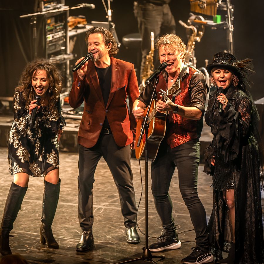 4 muzikanten/zangers on stage zingend. 