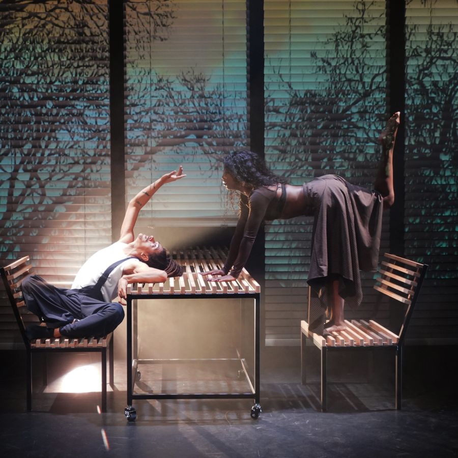 2 mensen buigen over een tafel heen en staan op een bankje naast de tafel.