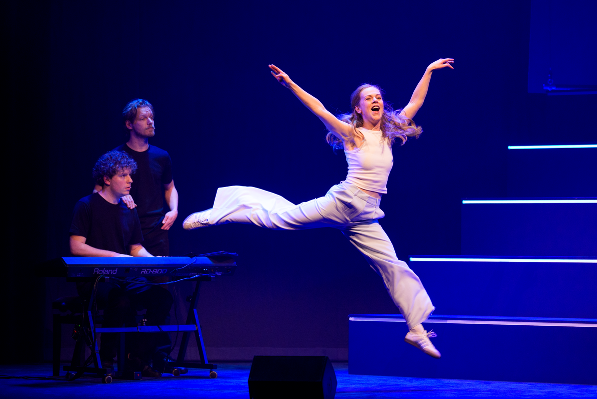 Lisa Ostermann springt in de lucht met haar benen wijd en haar armen omhoog. 