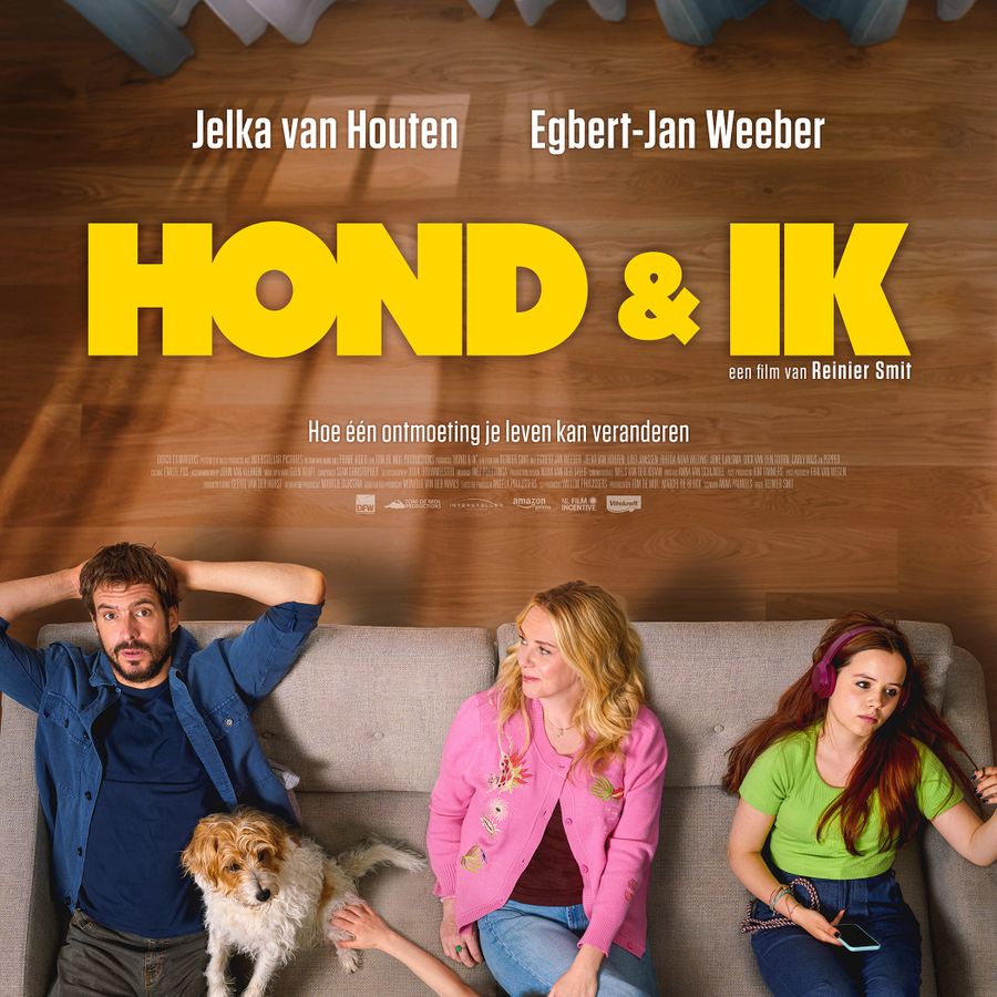 Filmaffiche met daarop de tekst Hond & Ik en een gezin bestaande uit 2 volwassenen en 2 kinderen zitten op een bank met naast zich een hond. 