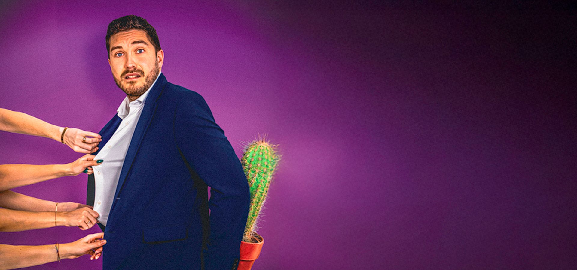Thijs Lindhout kijkt angstig naar de camera terwijl er vijf vrouwenhanden hem aan zijn overhemd trekken. Hij heeft een net pak aan en houdt een cactus achter hem. 