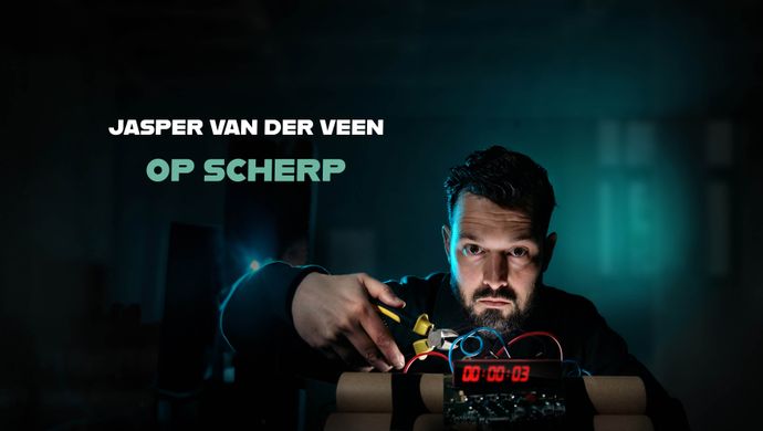 Jasper staat achter een tikkende bom met een tang om een draadje kapot te knippen. Hij kijkt serieus en de achtergrond is geheimzinnig doordat je niet veel ziet in een groene kleur. Bovenin staat de tekst: Jasper van der Veen op scherp.