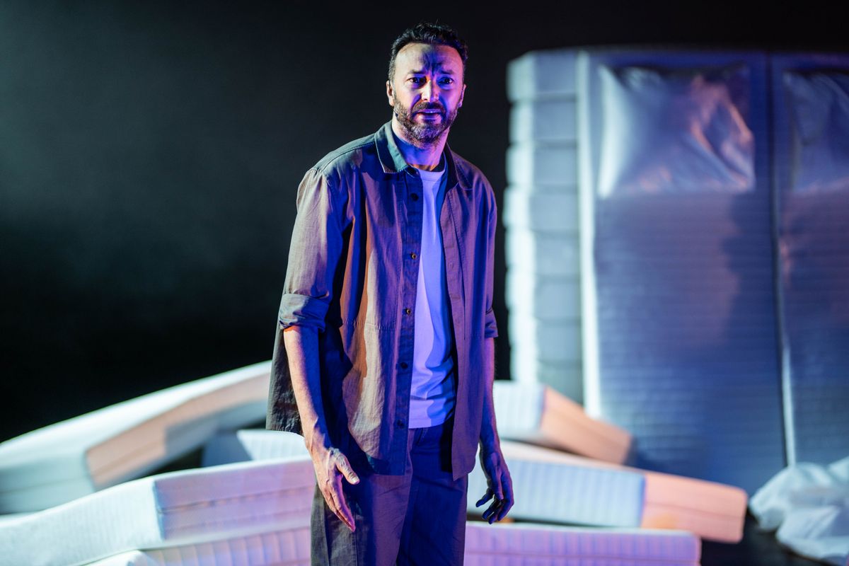 Een man in blauw licht kijkt peinzend voor zich uit. 