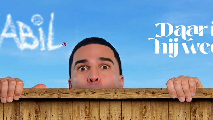 Nabil zijn hoofd komt net over een houten randje tevoorschijn. Hij houdt zich daaraan vast en ziet zijn vingers over het randje komen. Boven zijn hoofd is de blauwe lucht te zien met de witte tekst van een vliegtuig: Nabil. Daarnaast staat een witte tekst: Daar is hij weer.
