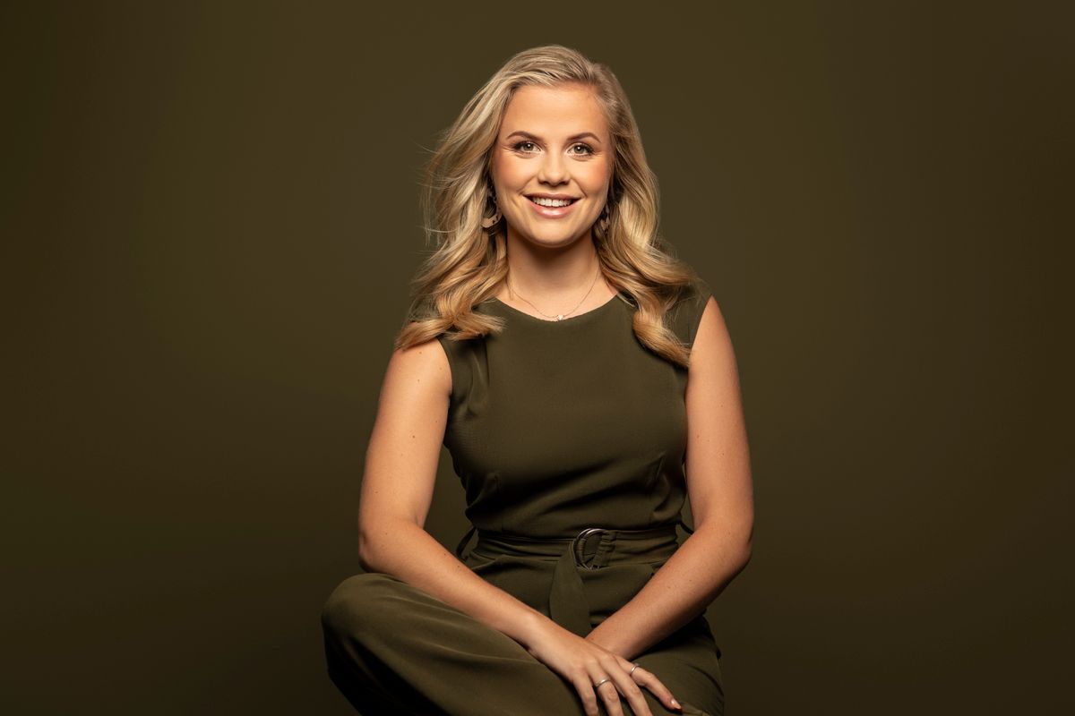 Yvonne kanters kijkt lachend de camera in. Ze staat voor een donkere achtergrond.