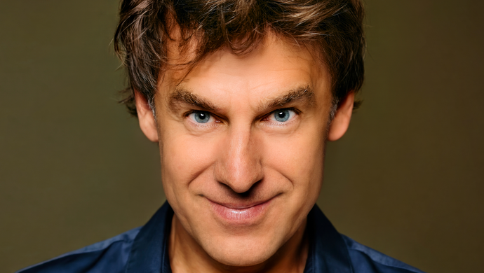 Remko kijkt half naar beneden met zijn ogen gericht op de camera en hij heeft een kleine glimlach.