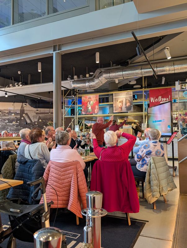 Een groep mensen dansen en zingen op de muziek.