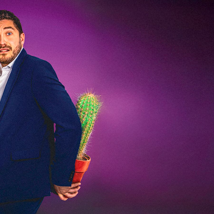 Thijs Lindhout kijkt angstig naar de camera terwijl er vijf vrouwenhanden hem aan zijn overhemd trekken. Hij heeft een net pak aan en houdt een cactus achter hem. 