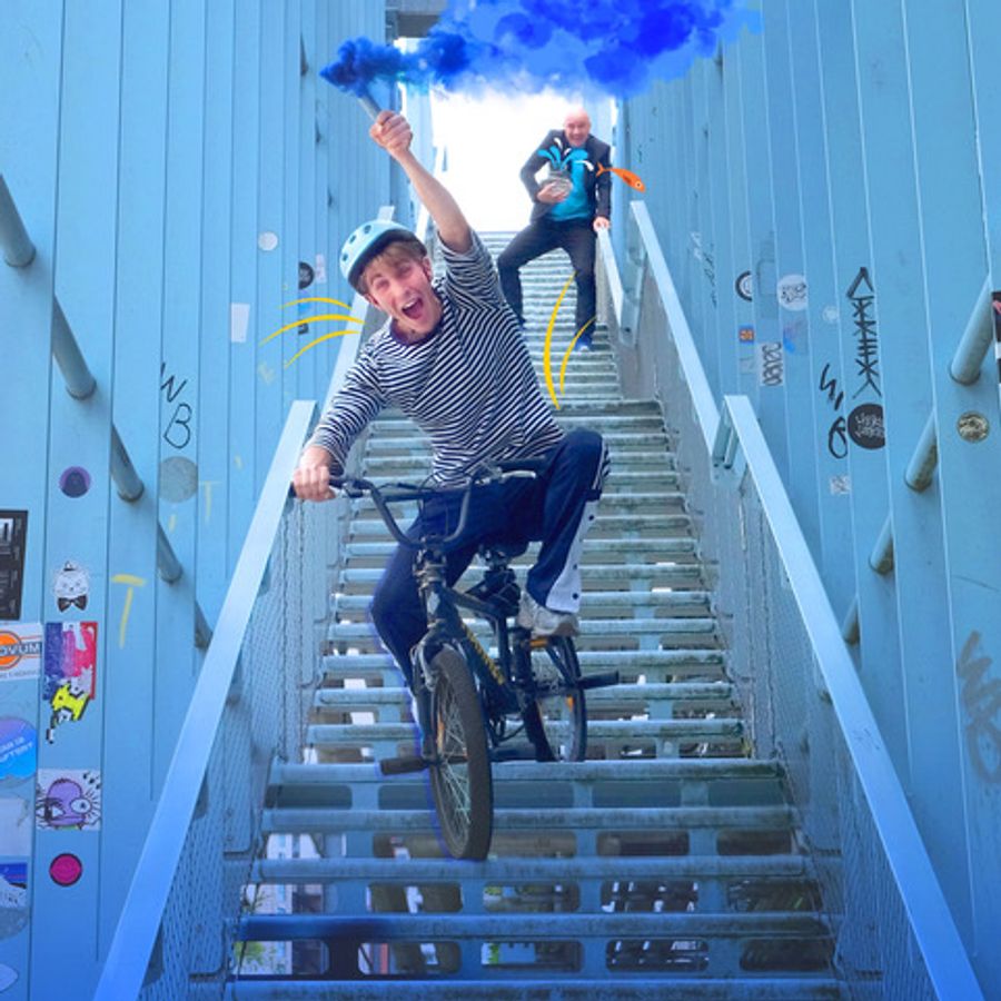 Jongen in streepjestrui die met z'n BMX fiets een trap af fietst. 